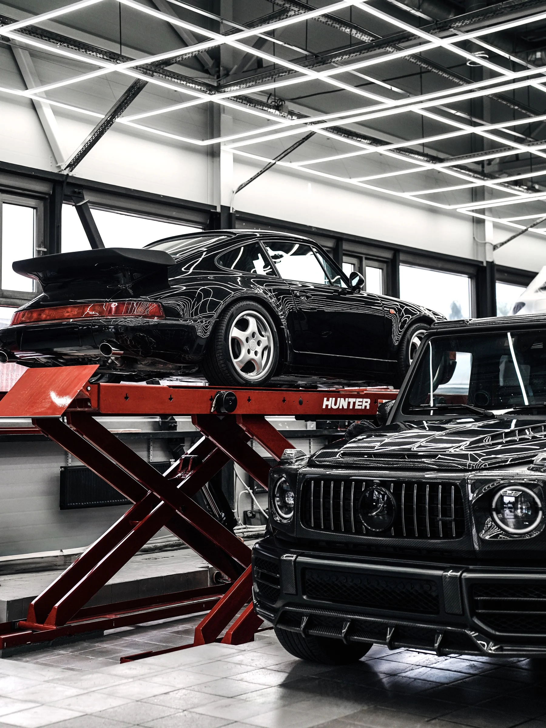 Классический Porsche на красном стенде рядом с Mercedes-Benz G-Class