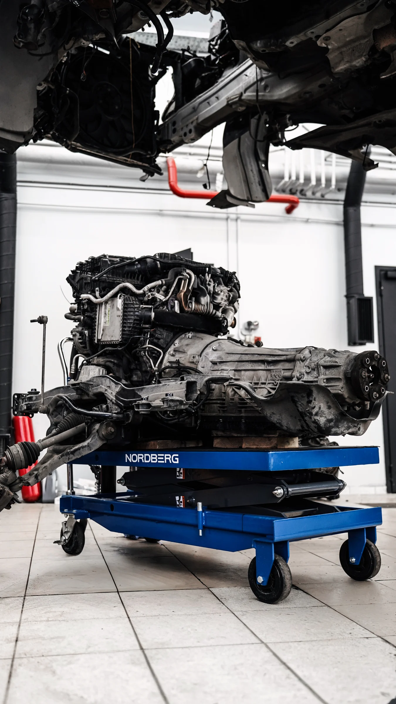 Автомобиль со снятым силовым агрегатом и двигатель с коробкой передач на ремонтном стенде